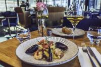 ベルゲンにあるマジック ホテル ソルハイムスビケンの2枚の皿に盛られた料理とグラス一杯のワインが置かれたテーブル