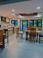 una cocina con mesas y sillas de madera en una habitación en Na Care Hotel, en Chaiyaphum
