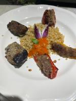 un plato blanco de comida con carne y arroz en Le Manoir des Remparts de Besse, en Besse-et-Saint-Anastaise