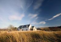 una gran casa blanca en un campo de hierba alta en Off The Hill B&amp;B, en Isleornsay