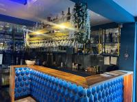 Un bar con un mostrador de madera y una pared azul. en Park Hotel Chalet, en Surami