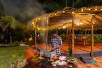 Een man staat onder een tent en bereidt eten op een tafel. bij Zostel Homes Kumta in Kumta