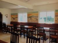 een eetkamer met tafels en stoelen en ramen bij Luxury 2BR Apartments in Kisumu