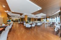 uma sala de jantar com mesas e cadeiras brancas e mesa de cabeceira em King Maker Grand Hotel-At the Gate of Tianmen Peak Cableway em Zhangjiajie