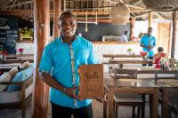Ein Mann hält in einem Restaurant ein Schild hoch. in der Unterkunft Natural Park Villa Resort in Pingwe
