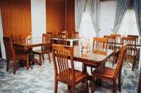 Un comedor con mesas y sillas de madera. en The Mason by Trovardig Guzape, en Abuja