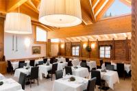 Un comedor con mesas blancas y sillas negras. en Hotel Orso Grigio, en Selva di Cadore