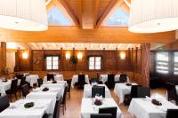 Un comedor con mesas blancas y sillas negras. en Hotel Orso Grigio, en Selva di Cadore