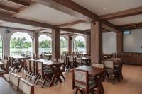 Un restaurante con mesas, sillas y ventanas. en Mayanadhi Resort, en Irimbranallūr