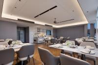 a restaurant with white tables and chairs and a kitchen at Huanman Hotel Jishou State Government Branch in Ganziping