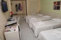 a hotel room with three beds and a television at JR Hotel in João Pessoa