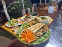 een houten tafel met borden met eten erop bij Buôn Gơ Rin in Láng Lớn