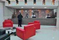 a lobby with red chairs and people at a counter at Skala Traveling Hotel in Cuiabá