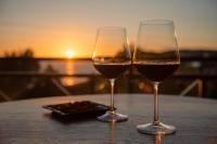 due bicchieri di vino seduti su un tavolo con il tramonto di Mounda Beach Retreat a Skala di Cefalonia