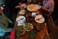 Un grupo de personas sentadas alrededor de una mesa de madera con comida. en Baias Wine, en Bagdatʼi