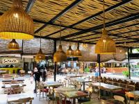 un restaurante con mesas, sillas y lámparas colgantes en Lyn Wood Estate, en Weligama