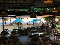 Un restaurante con mesas y sombrillas azules en la playa. en Lyn Wood Estate, en Weligama