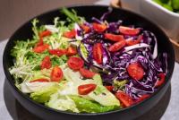 Eine schwarze Schüssel gefüllt mit einem Salat aus Kopfsalat und Tomaten. in der Unterkunft JI Hotel Chongqing Yufu Industrial Park TuoXinXing Times in Chongqing