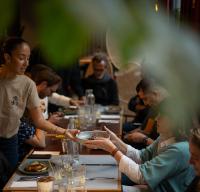 Un grupo de personas sentadas en una mesa comiendo comida en Le Grand Quartier, en París