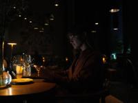 a woman sitting at a table in a dark room at KOS Pilar Hotel in Pilar