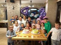 eine Gruppe von Kindern steht mit einer Geburtstagstorte um einen Tisch herum in der Unterkunft Вила Вяра, Надежда, Любов in Neofit Rilski