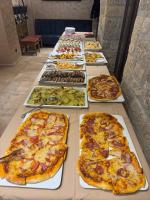 ein langer Tisch mit mehreren Pizzen darauf in der Unterkunft Вила Вяра, Надежда, Любов in Neofit Rilski