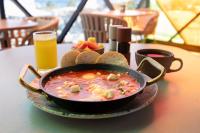 a bowl of soup with bread and a glass of orange juice at Prixma Hotel in San Andrés