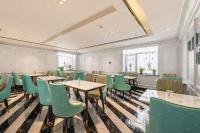 ein Esszimmer mit Tischen und grünen Stühlen in der Unterkunft Manyueju Hotel 