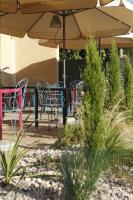 Un patio con mesas y sillas y una sombrilla. en Auberge Bressane de Buellas, en Buellas