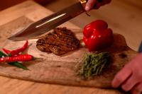 iemand die een biefstuk op een snijplank snijdt met een mes bij hotel de ville de Rossinière in Rossinière
