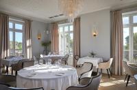 a restaurant with white tables and chairs and windows at Château Capitoul in Narbonne