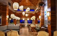 ein Restaurant mit Tischen, Stühlen und Kronleuchtern in der Unterkunft Naïa Resort and Spa in Placencia Village