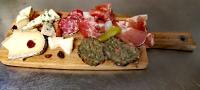Una tabla de cortar con diferentes tipos de queso y carne. en Hôtel Rose des Vents, en Baix