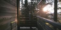 a woman walking down a wooden stairs with the sun in the background at Cabane entre terre et ciel in Saint-Nicolas-la-Chapelle