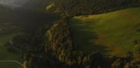 a green field with a house on a hill with trees at Cabane entre terre et ciel in Saint-Nicolas-la-Chapelle