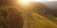 a road on the side of a hill with the sun setting at Cabane entre terre et ciel in Saint-Nicolas-la-Chapelle