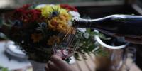 a person pouring wine into a glass with flowers at Cabane entre terre et ciel in Saint-Nicolas-la-Chapelle