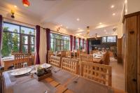 un ristorante con tavoli e sedie in legno e finestre di Echor Himalayan Retreat Ranikhet a Rānīkhet