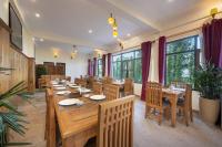 un ristorante con tavoli e sedie in legno e finestre di Echor Himalayan Retreat Ranikhet a Rānīkhet