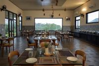 een restaurant met tafels en stoelen en een groot raam bij Sonemale Resort Chikmagalur in Mudigere