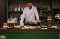 Ein Mann steht in einer Küche mit einem Buffet. in der Unterkunft RUELLE Chateau Boutique in Sinaia