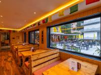een restaurant met houten banken en een groot raam bij The Hosteller Mcleodganj in McLeod Ganj
