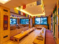 een restaurant met houten tafels, banken en ramen bij The Hosteller Mcleodganj in McLeod Ganj