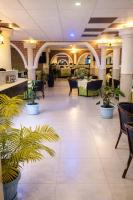 een lobby met tafels en stoelen en potplanten bij Hôtel Santa Lucia in Yaoundé
