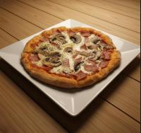 a pizza sitting on a white plate on a table at Hostal Luz de Luna in Palomino