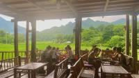 枚州县Meadow Mai Chau Homestay的一群坐在门廊桌子上的人