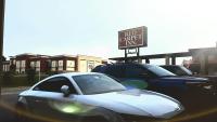 a white car parked in front of a sign at Red Carpet Inn - Blacksburg in Blacksburg