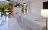 a bedroom with a bed and a balcony with a table at Angra Boutique Hotel in Angra dos Reis