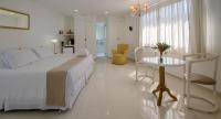 a white bedroom with a bed and a table at Angra Boutique Hotel in Angra dos Reis
