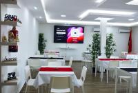 a restaurant with white tables and white chairs and a screen at Onzo Yamy in Luanda